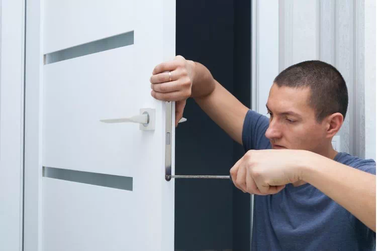 Homme en train de remonter une poignée de porte avec un tournevis